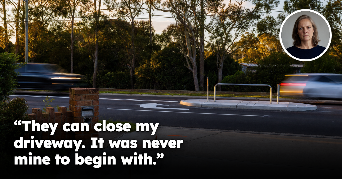 A residential driveway meeting a busy Australian arterial road, with new line-marking, a concrete median and surveyor's pegs on the concrete apron.