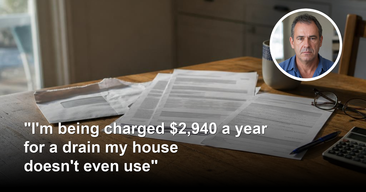 An opened council rates notice and printed statement on a suburban kitchen table beside a mug of tea, reading glasses and a calculator in early morning light