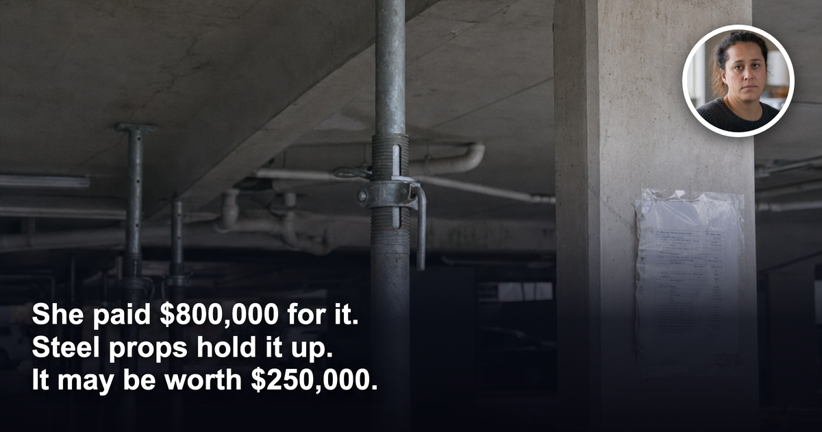 Temporary steel props bracing a badly cracked concrete beam in an apartment building car park, with an orange safety barrier and a laminated engineering notice